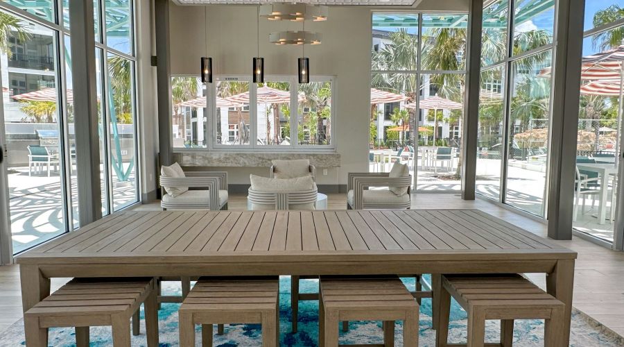 Modern wood table with designer lighting and floor-to-ceiling windows facing the pool