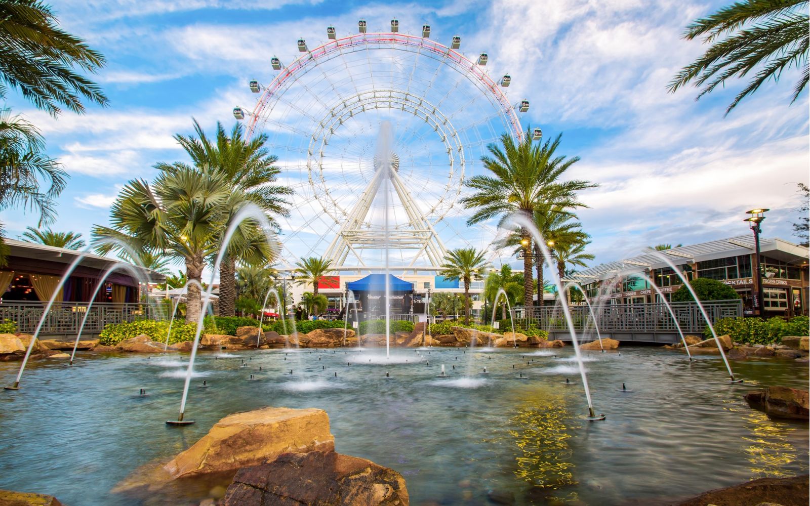 Large ferris wheel behind a pool, fountain, and palm trees in Orlando, Fl