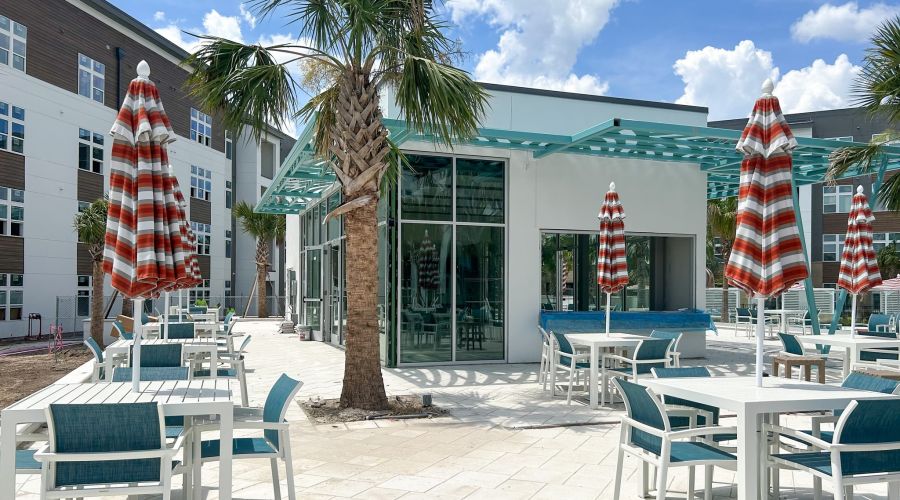 Indoor/outdoor jewel box pavilion resident amenity with surrounding tables and palm trees