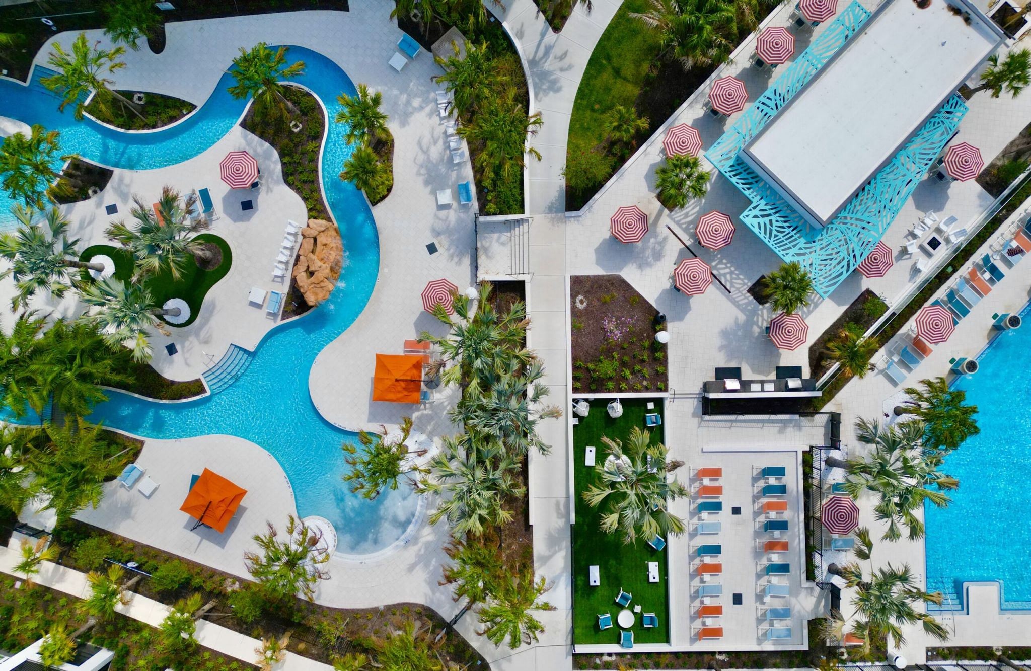 Aerial view of our pools with in-pool lounge chairs and pool deck with chairs and cabanas