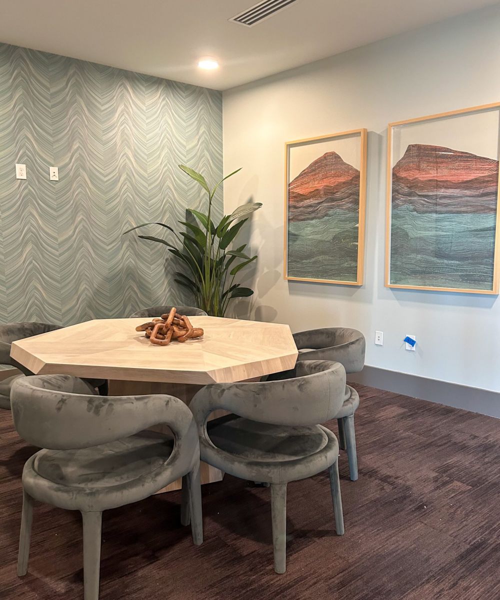 Furnished co-working space with two large paintings and a hexagon shaped table with chairs