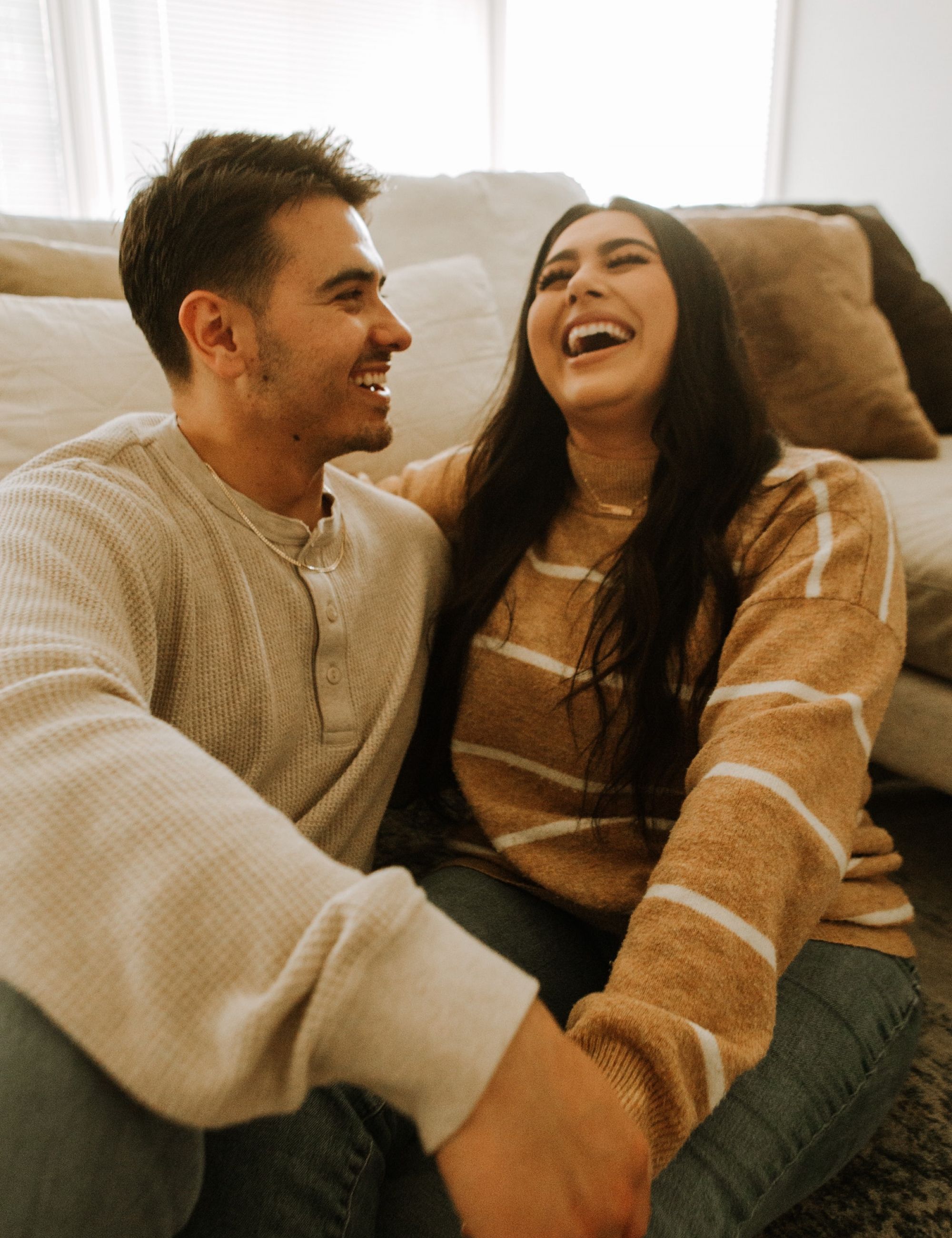 Latin couple sitting on floor laughing and smiling