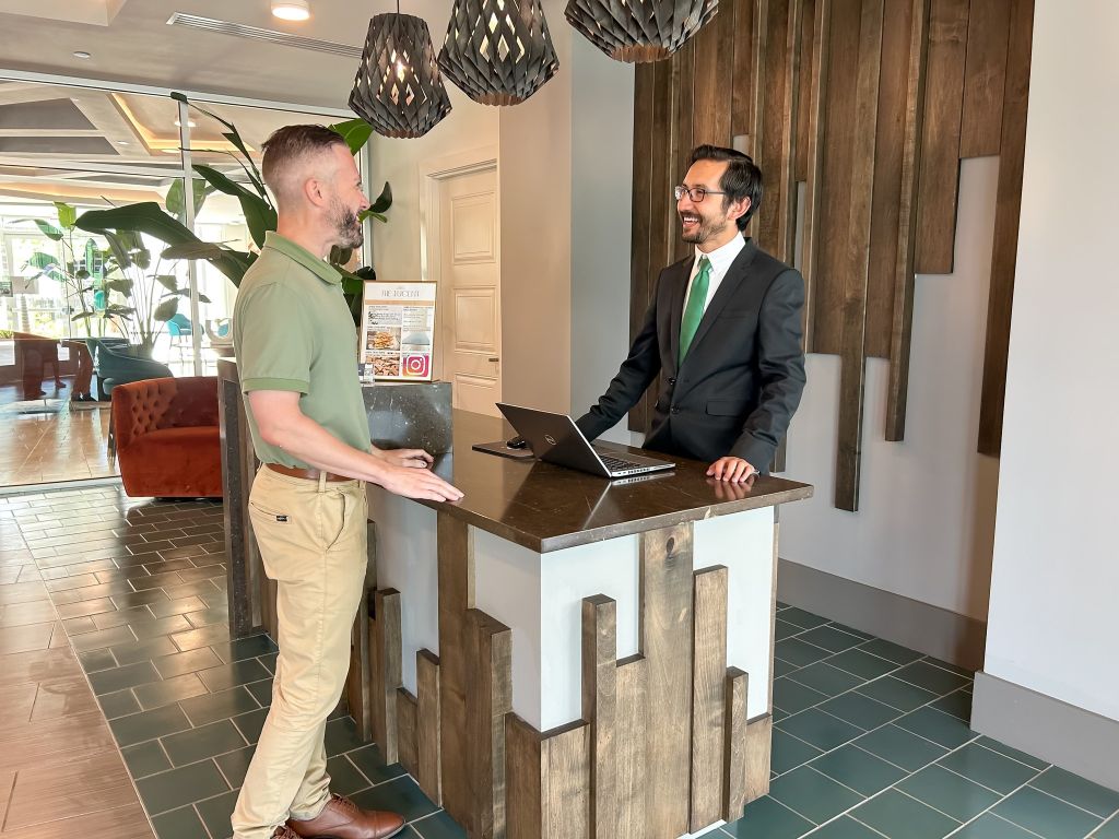 On-site concierge for The Lucent at Sunrise residents and their guests, man standing at counter helping apartment resident