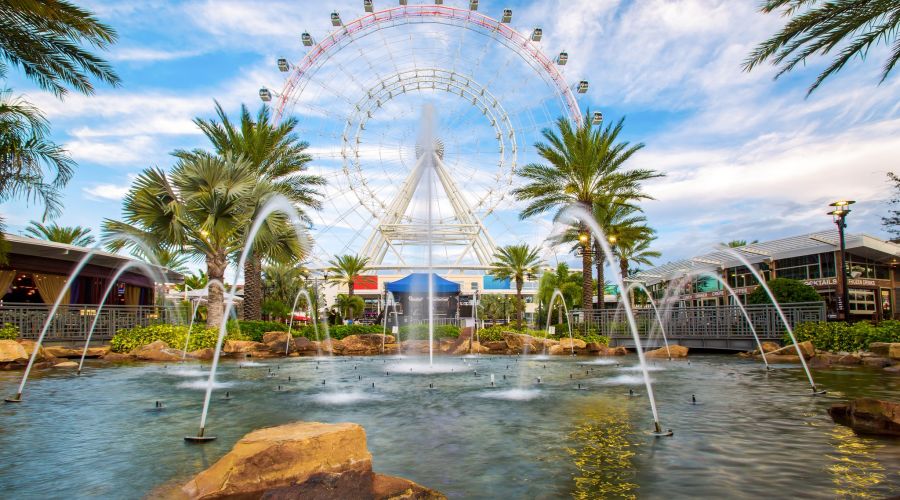 Large ferris wheel behind a pool, fountain, and palm trees in Orlando, Fl