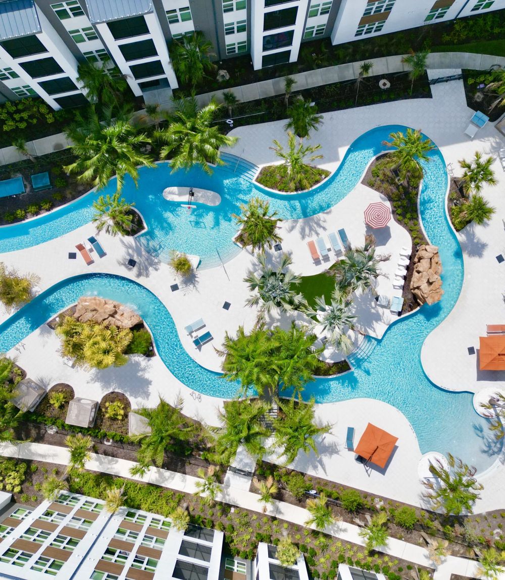 Lazy river surrounded by lush green trees with The Lucent at Sunrise apartment building next to it