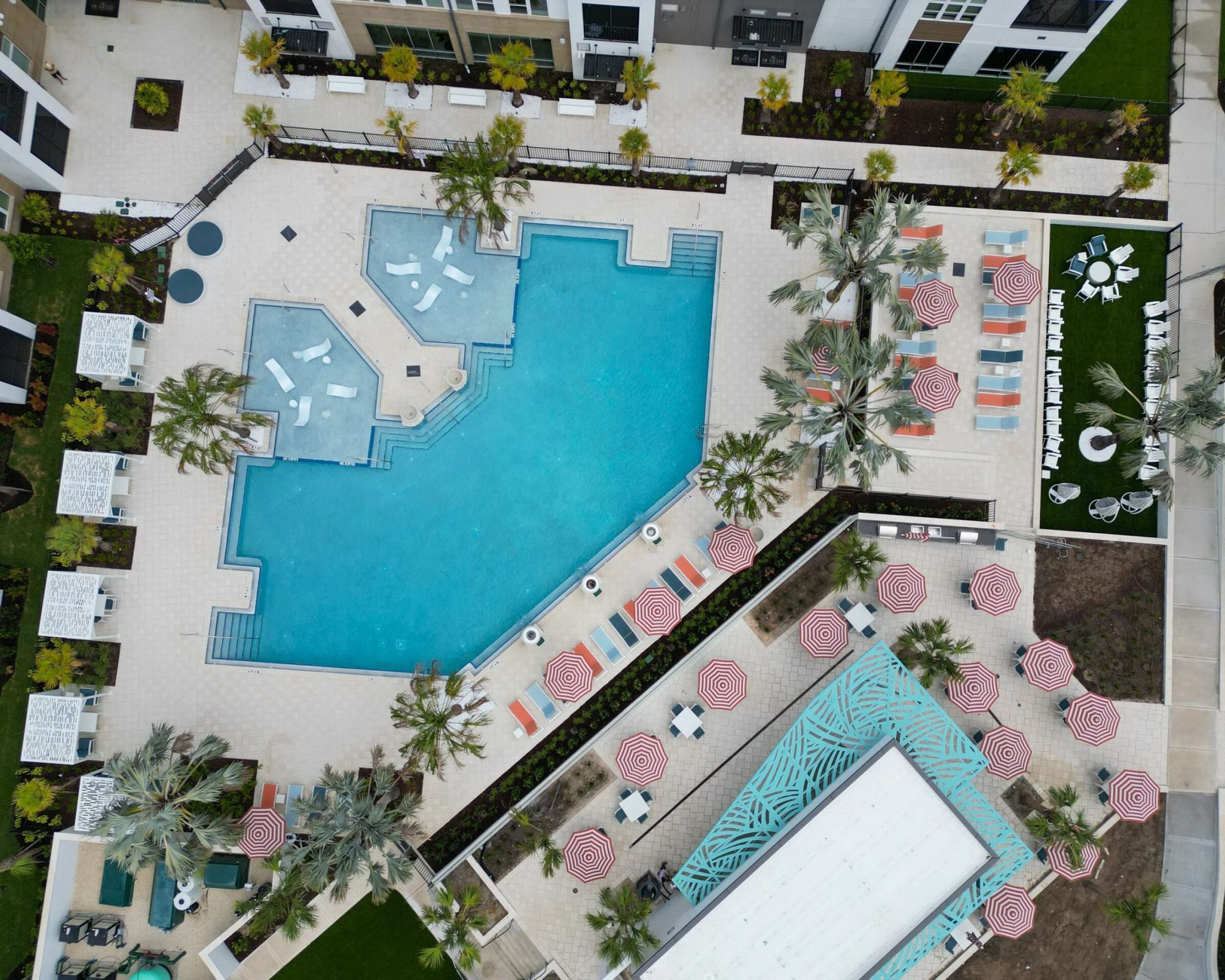 Aerial of the zero entry pool surrounded by lounge chairs and foliage at The Lucent at Sunrise Apartments