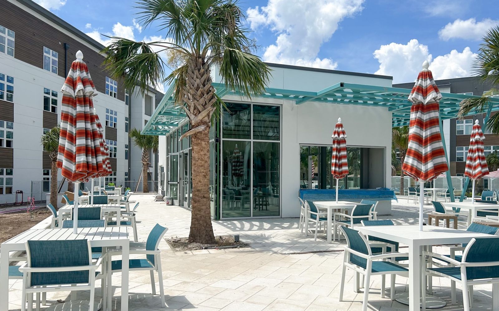 Indoor/outdoor jewel box pavilion resident amenity with surrounding tables and palm trees