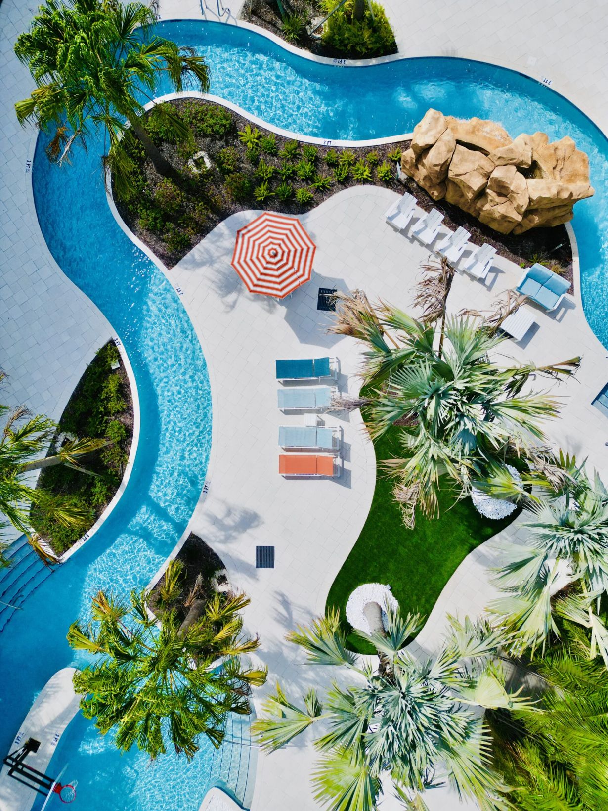 Aerial view of our 23,000 sq. ft. lazy river surrounded by trees and lounge chairs at The Lucent at Sunrise