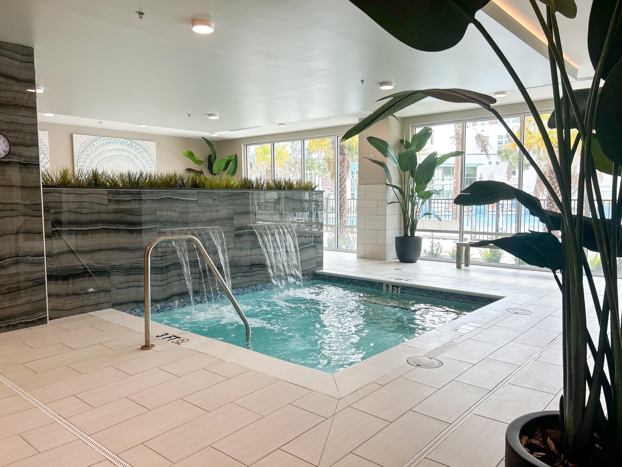 Indoor hot tub apartment amenity with integrated fountain and beautiful gray tile backsplash