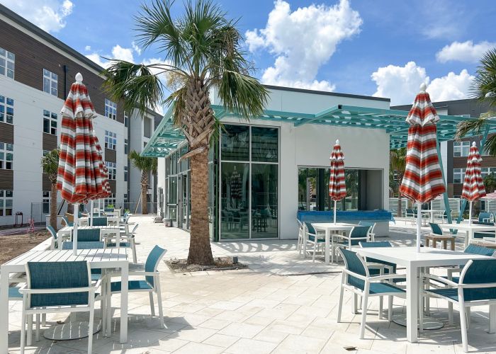 Indoor/outdoor jewel box pavilion resident amenity with surrounding tables and palm trees