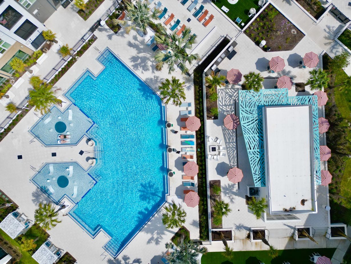 Aerial view of our pools with in-pool lounge chairs and pool deck with chairs and cabanas