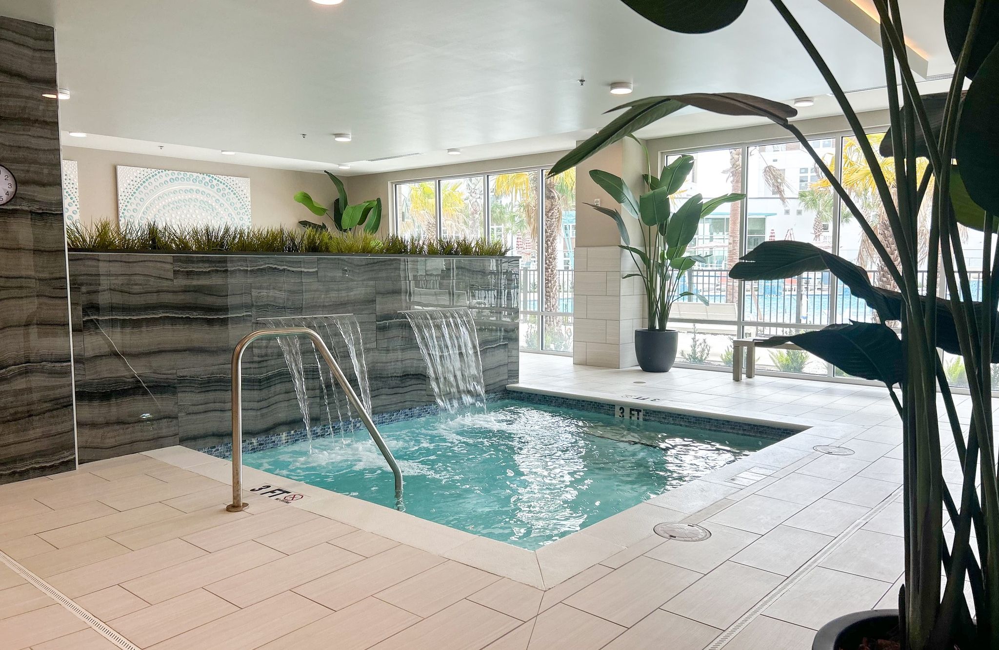 Indoor hot tub apartment amenity with integrated fountain and beautiful gray tile backsplash