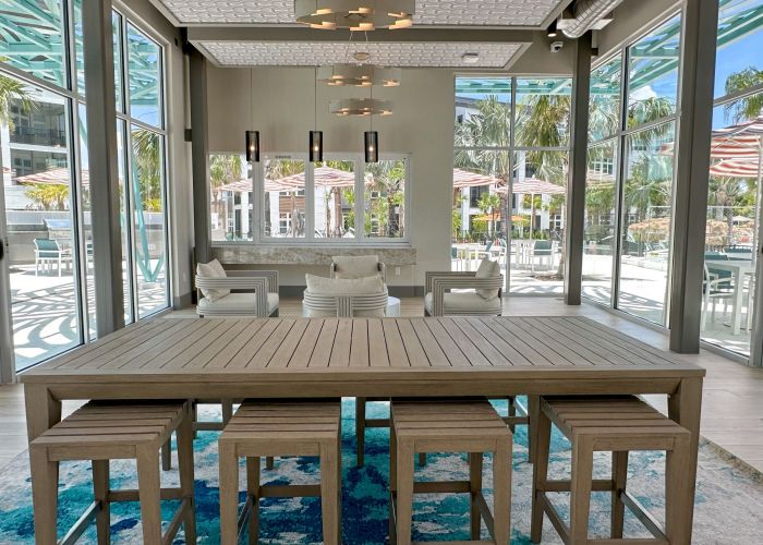 Modern wood table with designer lighting and floor-to-ceiling windows facing the pool