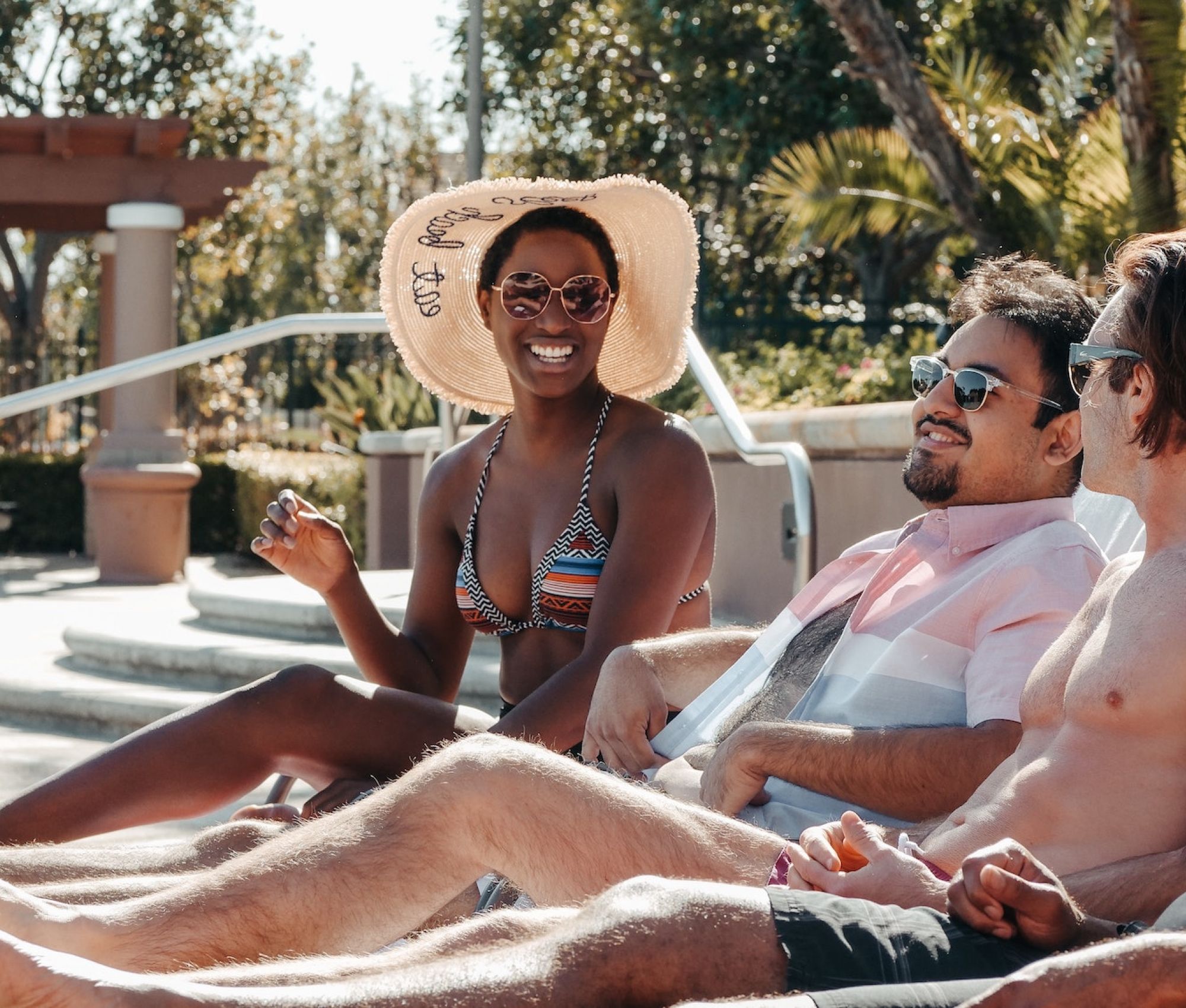 friends smiling while lounging by apartment pool in Kissimmee, FL
