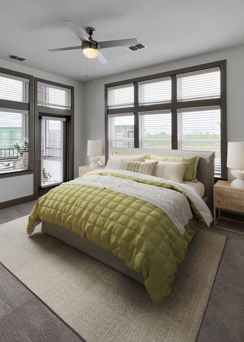 Furnished bedroom with carpet, king sized bed, large windows, and a door leading to a covered balcony at The Lucent at Sunrise.